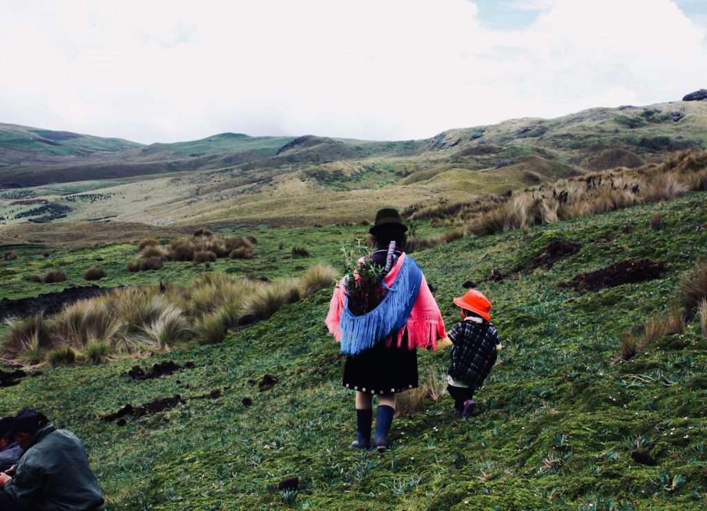 Indigenous people walk a mountainside