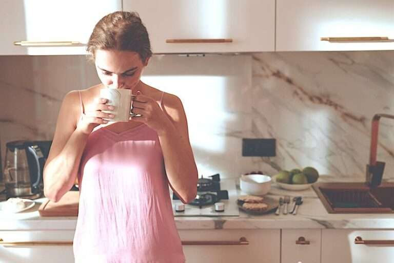a woman drinks coffee in the kitchen