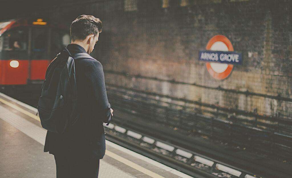 man wearing backpack at a subway station