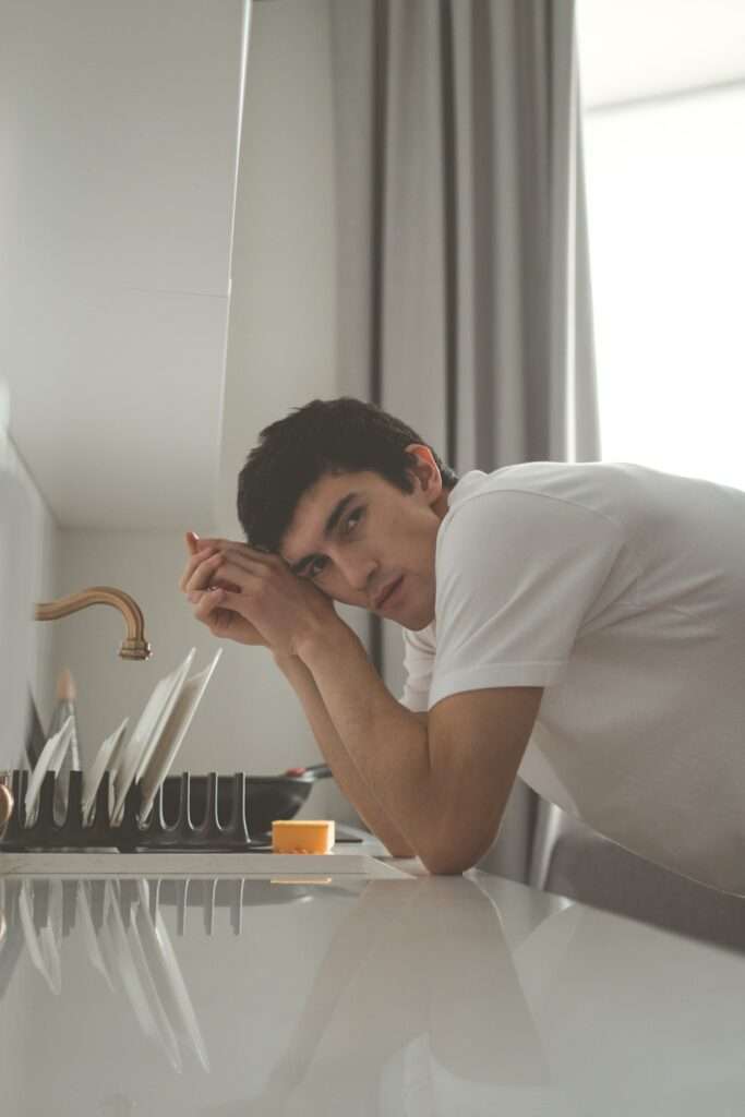 A man leans on kitchen counter.