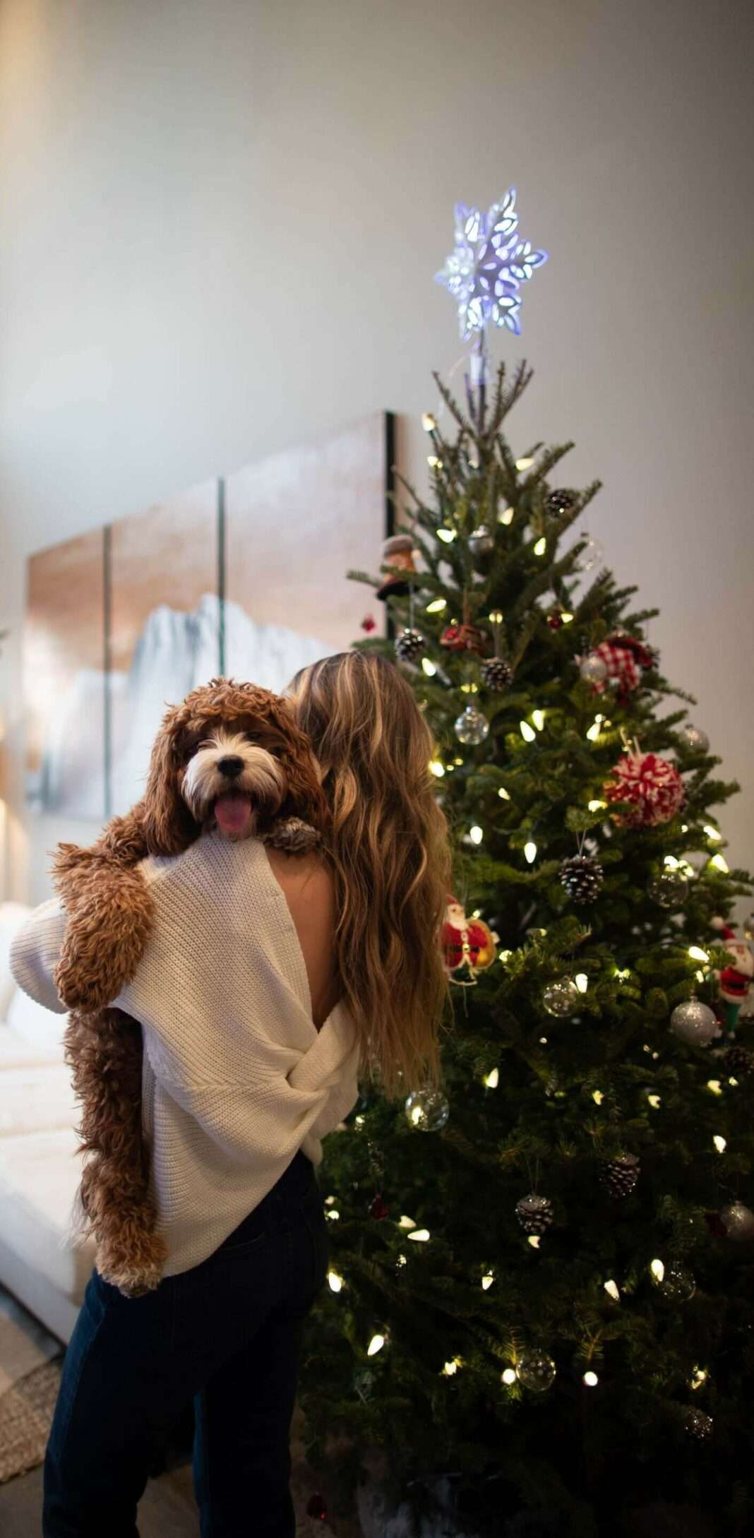 woman holding dog by Christmas tree