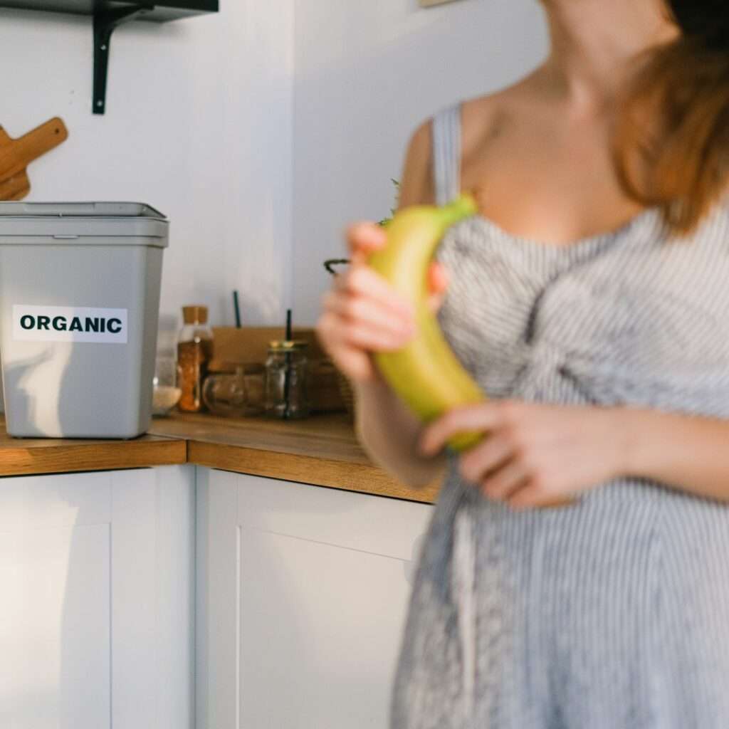 compost bin and woman holding a banana