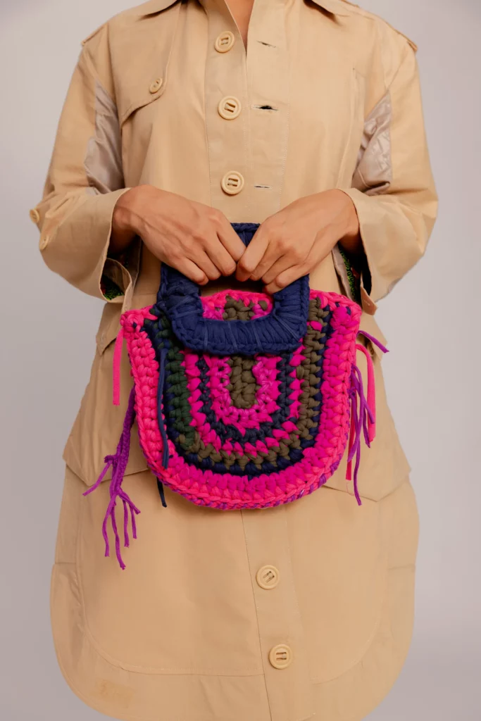 Model holds handbag.