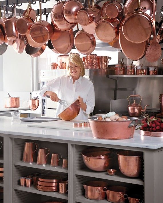 Martha Stewart surrounded by copper cookware.